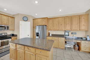 Kitchen with a kitchen island, recessed lighting, light brown cabinets, and stainless steel appliances