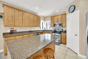 Kitchen with a center island, a kitchen bar, recessed lighting, stainless steel appliances, and a sink