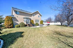 Rear view of house with stucco siding, a patio, fence, a yard, and french doors