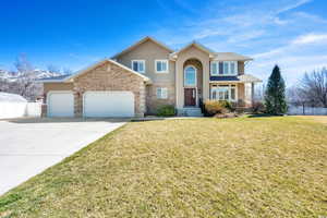 Traditional-style home with stucco siding, a front lawn, driveway, fence, and a garage