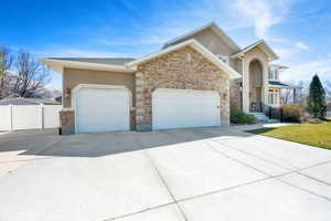 View of front of house featuring brick siding, fence, a garage, and driveway