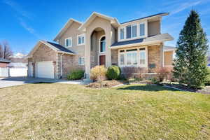 Traditional-style home with brick siding, an attached garage, a front lawn, and fence