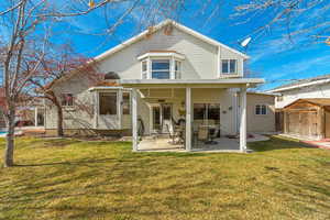 Back of house featuring a patio area, a lawn, a storage unit, and an outdoor structure