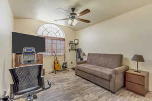Interior space featuring a ceiling fan, vaulted ceiling, wood finished floors, and baseboards