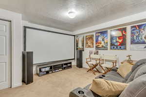 Carpeted home theater room featuring a textured ceiling