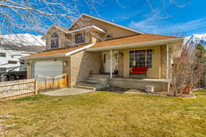 View of front of house featuring brick siding, a shingled roof, fence, a front yard, and covered porch