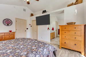 Bedroom featuring visible vents, ceiling fan, lofted ceiling, light wood-style flooring, and ensuite bathroom