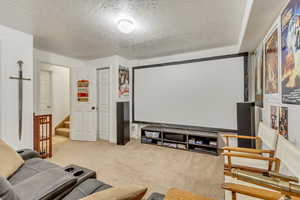 Carpeted home theater room with a textured ceiling