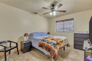 Bedroom featuring visible vents, baseboards, light wood-style floors, and a ceiling fan