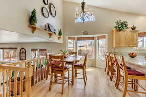 Dining room with a high ceiling, a notable chandelier, light wood-style floors, and baseboards