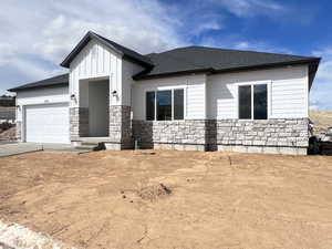 View of front facade with driveway, stone siding, roof with shingles, board and batten siding, and a garage