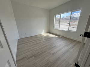 Spare room featuring visible vents, baseboards, and light wood-type flooring