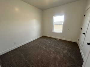Unfurnished bedroom featuring baseboards and dark carpet