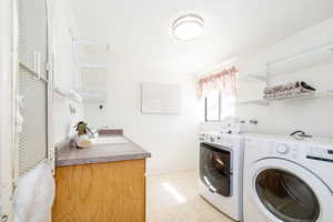 Laundry area featuring washer and clothes dryer, laundry area, baseboards, and a sink