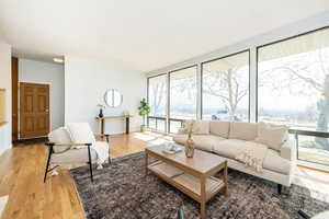 Living room featuring a wall of windows, baseboards, and light wood-style floors