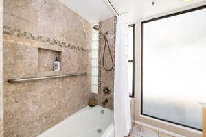 Bathroom featuring a wealth of natural light, shower / tub combo, and tile patterned flooring