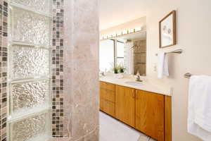 Bathroom with a sink, tiled shower, and double vanity