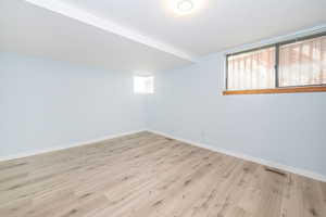 Empty room featuring visible vents, baseboards, and light wood-type flooring