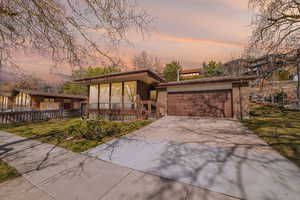 Mid-century home featuring driveway, brick siding, and a front lawn