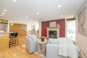 Living area with light wood finished floors, recessed lighting, a tile fireplace, and baseboards