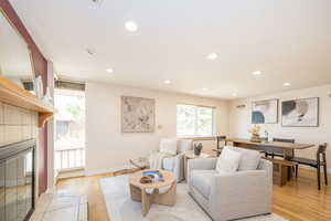 Living room featuring recessed lighting, baseboards, a tiled fireplace, and light wood finished floors