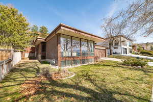 Back of property with a lawn, fence, concrete driveway, a garage, and brick siding