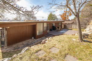 Rear view of house with a deck, a yard, and fence