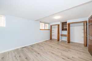 Unfurnished bedroom with light wood finished floors, visible vents, baseboards, and multiple closets