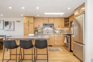 Kitchen with open shelves, stainless steel appliances, light brown cabinets, and a sink