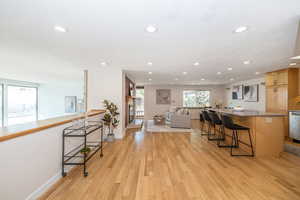 Kitchen with a kitchen bar, light wood-style flooring, recessed lighting, and open floor plan