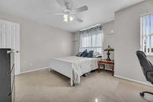 Bedroom featuring light carpet, baseboards, and a ceiling fan