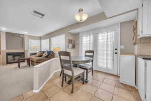 Dining area with light carpet, visible vents, a fireplace, and baseboards