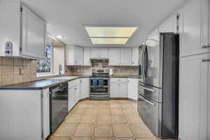 Kitchen with a sink, stainless steel appliances, backsplash, and dark countertops