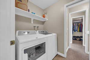 Laundry room featuring light tile patterned floors, laundry area, washer and dryer, and baseboards