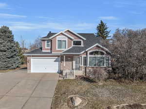 View of front of home with roof with shingles, a porch, concrete driveway, a garage, and brick siding