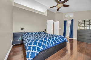 Primary Bedroom featuring ceiling fan, baseboards, lofted ceiling, and wood finished floors