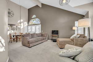 Living room featuring baseboards, beam ceiling, high vaulted ceiling, and carpet flooring