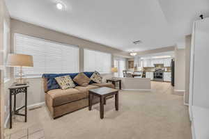 Living room with visible vents, baseboards, and light colored carpet