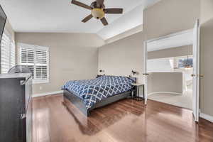 Primary Bedroom featuring vaulted ceiling, wood finished floors, and baseboards