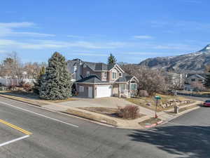 View of front of home with driveway, a mountain view, roof with shingles, a garage, and brick siding