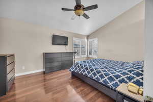 Primary Bedroom featuring baseboards, a ceiling fan, lofted ceiling, and wood finished floors