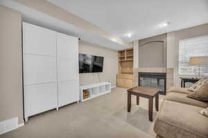 Living area featuring baseboards, a fireplace, visible vents, and light carpet