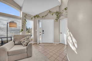 Entryway featuring lofted ceiling, light tile patterned flooring, and baseboards