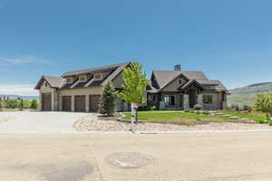 View of front of home with stone siding, driveway, a mountain view, and a chimney
