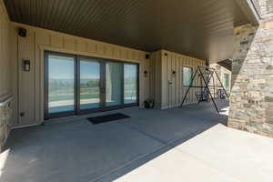 Entrance to property with a patio, board and batten siding, stone siding, and sliding doors