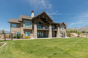 Back of house featuring a balcony, stone siding, board and batten siding, a chimney, and a mountain view