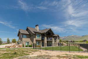 Rear view of property with a balcony, a mountain view, a chimney, stone siding, and roof with shingles