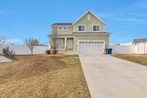 Traditional home with fence, board and batten siding, a porch, and an attached garage