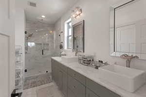 Bathroom with a sink, visible vents, a marble finish shower, and marble finish floor