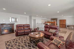 Living room featuring recessed lighting, light wood-style floors, and a glass covered fireplace